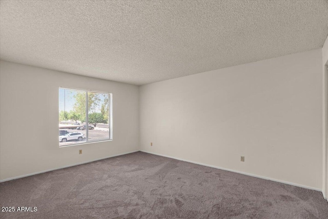 carpeted empty room featuring a textured ceiling and baseboards