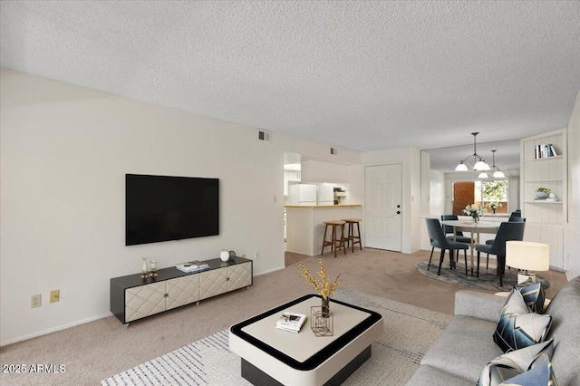 carpeted living area featuring a textured ceiling, a chandelier, and baseboards