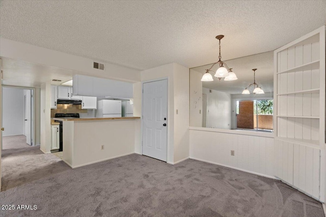 kitchen featuring freestanding refrigerator, carpet floors, under cabinet range hood, hanging light fixtures, and a chandelier