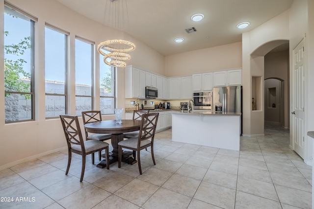 tiled dining room featuring a chandelier, a towering ceiling, and sink