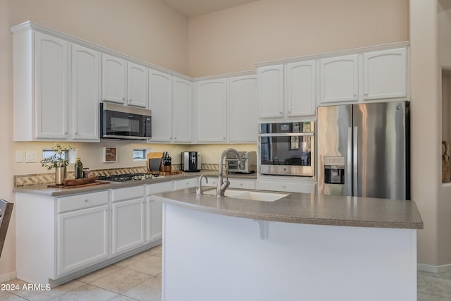 kitchen with sink, white cabinetry, a kitchen island with sink, stainless steel appliances, and light tile patterned floors