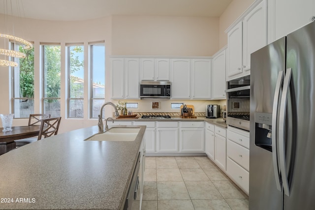 kitchen with decorative light fixtures, sink, white cabinetry, appliances with stainless steel finishes, and light tile patterned floors