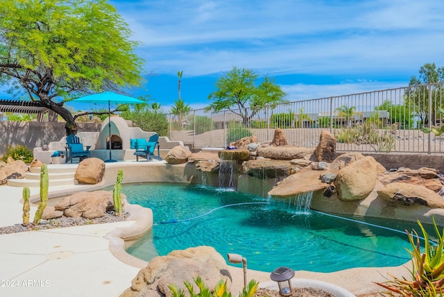 view of pool with pool water feature, a tile fireplace, and a patio