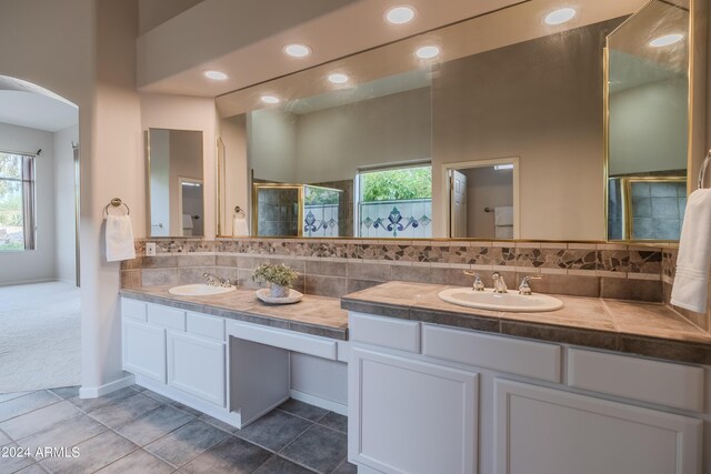 bathroom with an enclosed shower, vanity, and tasteful backsplash