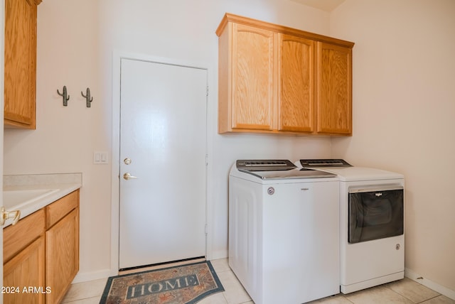 laundry area with washing machine and dryer, cabinets, light tile patterned floors, and sink