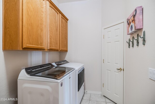 washroom featuring washing machine and dryer, cabinets, and light tile patterned floors