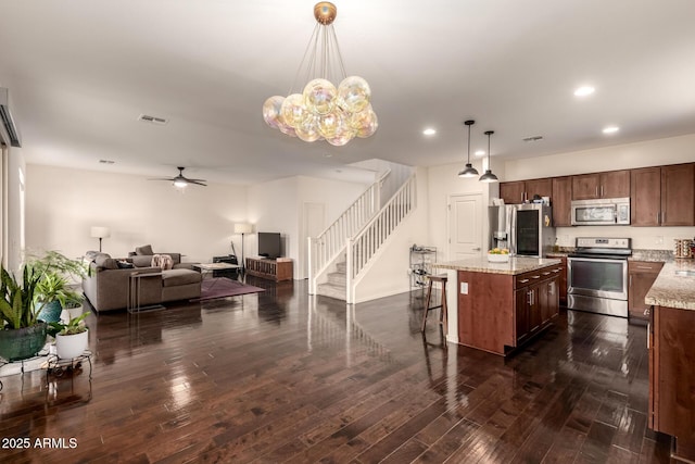 2149 E Aire Libre Ave, Phoenix, AZ 85022 - kitchen featuring stainless steel appliances, open floor plan, ceiling fan, dark wood-type flooring, and a breakfast bar area