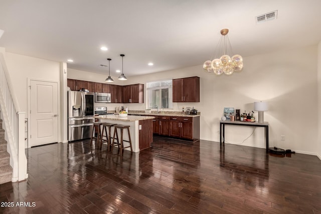 2149 E Aire Libre Ave, Phoenix, AZ 85022 - kitchen featuring appliances with stainless steel finishes, dark wood-type flooring, dark brown cabinets, a kitchen island, and recessed lighting