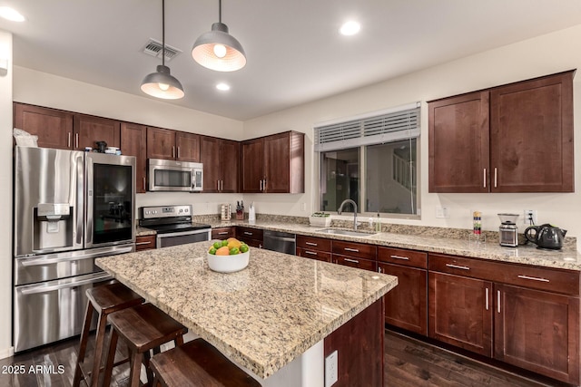 2149 E Aire Libre Ave, Phoenix, AZ 85022 - kitchen with stainless steel appliances, a breakfast bar area, dark wood-style flooring, light stone counters, and recessed lighting