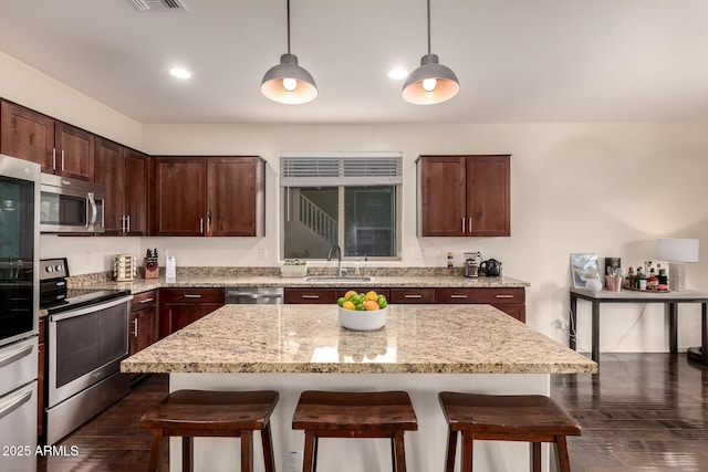 2149 E Aire Libre Ave, Phoenix, AZ 85022 - kitchen with stainless steel appliances, a breakfast bar, dark wood finished floors, dark brown cabinets, and light stone countertops