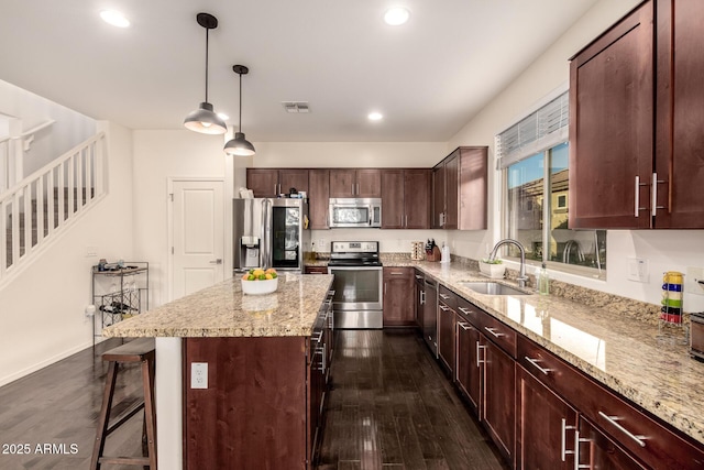 2149 E Aire Libre Ave, Phoenix, AZ 85022 - kitchen with appliances with stainless steel finishes, dark wood-style flooring, a kitchen island, recessed lighting, and a kitchen bar