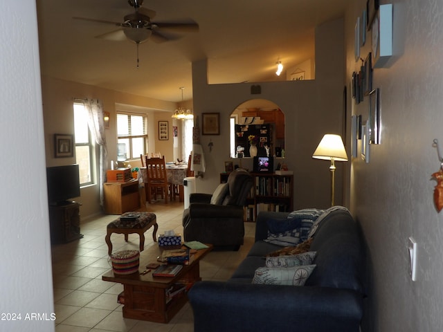 living room featuring lofted ceiling, ceiling fan with notable chandelier, and light tile patterned floors