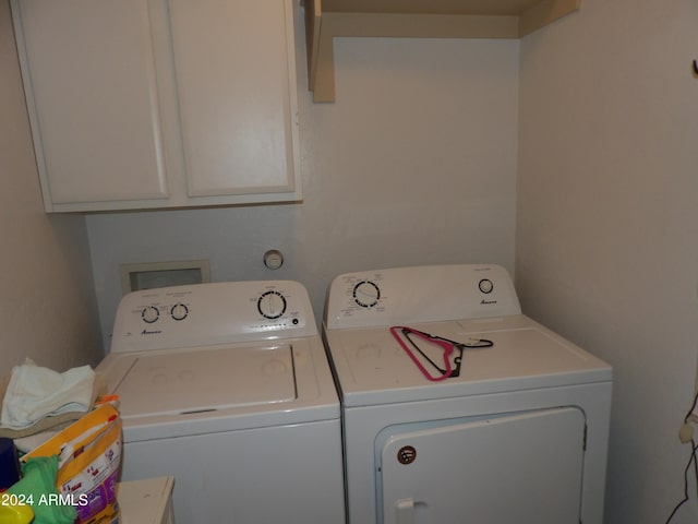 clothes washing area with washer and dryer and cabinets