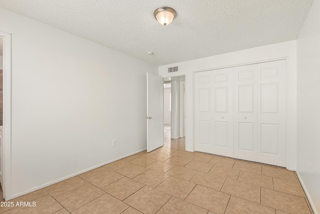 unfurnished bedroom with light tile patterned flooring, a textured ceiling, and a closet