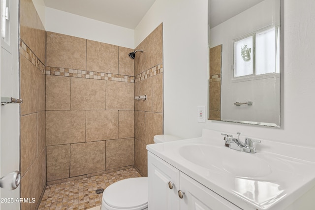 bathroom with vanity, toilet, and tiled shower