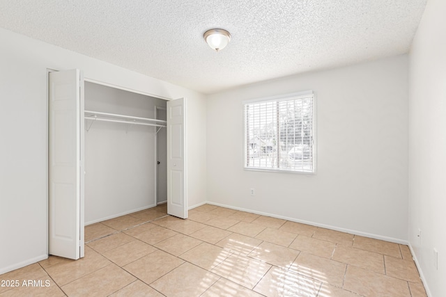 unfurnished bedroom with light tile patterned flooring, a textured ceiling, and a closet