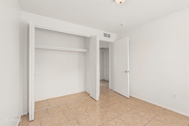 unfurnished bedroom with light tile patterned floors, a closet, and a textured ceiling