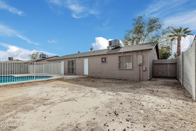 back of property featuring central AC and a fenced in pool