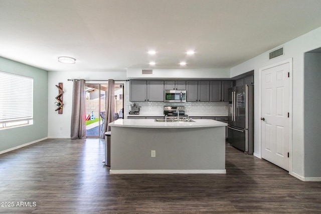 13709 W Rovey Ave, Litchfield Park, AZ 85340 - kitchen featuring stainless steel appliances, gray cabinets, light countertops, decorative backsplash, and a center island with sink