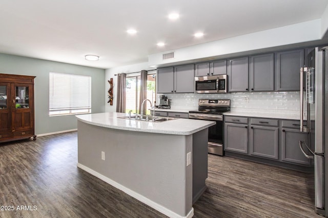 13709 W Rovey Ave, Litchfield Park, AZ 85340 - kitchen with stainless steel appliances, a sink, gray cabinetry, tasteful backsplash, and dark wood-type flooring