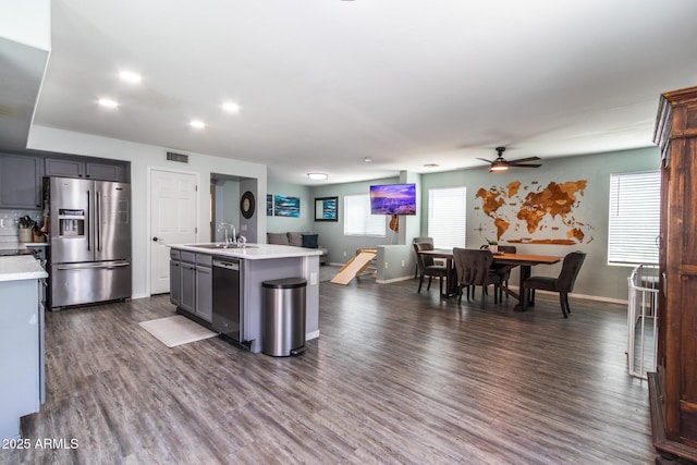 13709 W Rovey Ave, Litchfield Park, AZ 85340 - kitchen featuring stainless steel appliances, light countertops, a ceiling fan, an island with sink, and dark wood finished floors