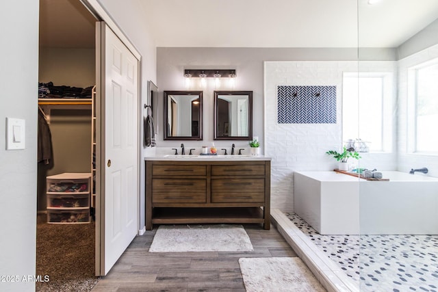 13709 W Rovey Ave, Litchfield Park, AZ 85340 - bathroom featuring double vanity, wood finished floors, a freestanding tub, and a walk in closet