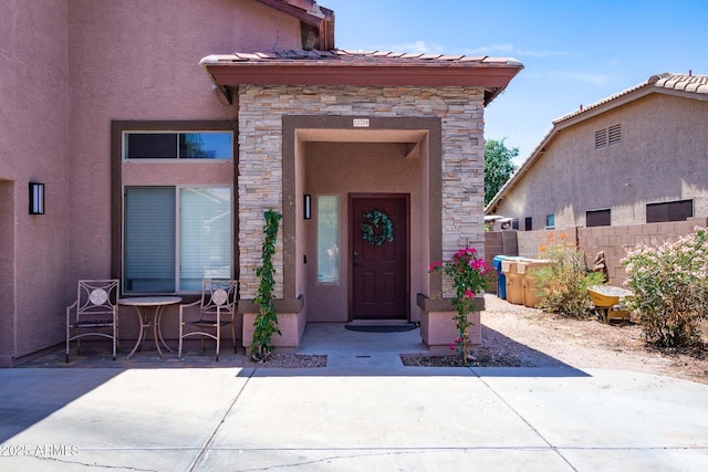 13709 W Rovey Ave, Litchfield Park, AZ 85340 - view of exterior entry with stone siding, stucco siding, and a patio area