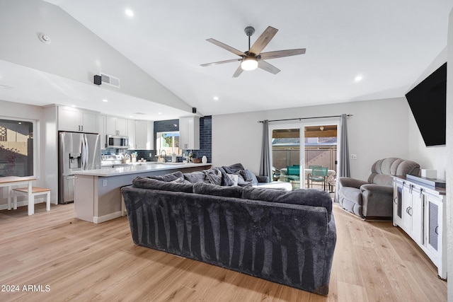 living room with ceiling fan, light hardwood / wood-style flooring, high vaulted ceiling, and sink