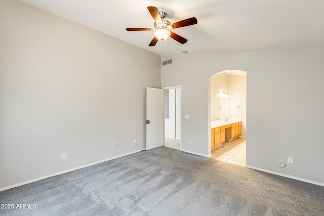 1037 E Baylor Ln, Gilbert, AZ 85296 - unfurnished bedroom featuring arched walkways, light carpet, vaulted ceiling, ensuite bath, and ceiling fan