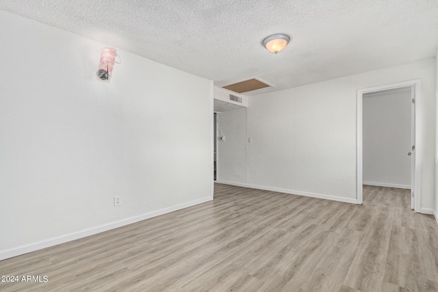 spare room with light wood-type flooring and a textured ceiling