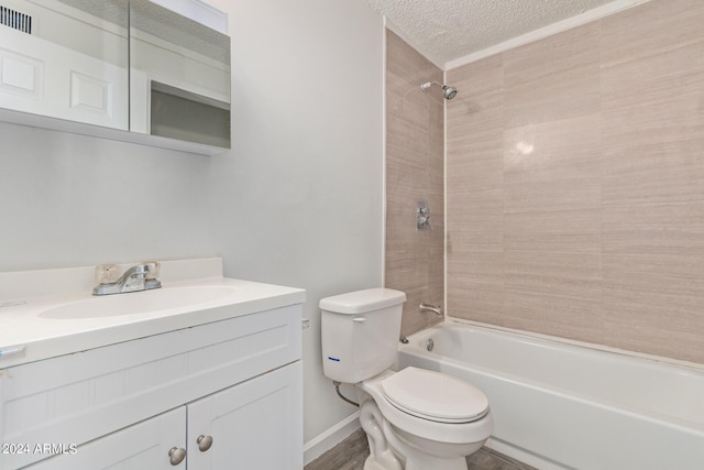 full bathroom featuring a textured ceiling, vanity, toilet, and tiled shower / bath