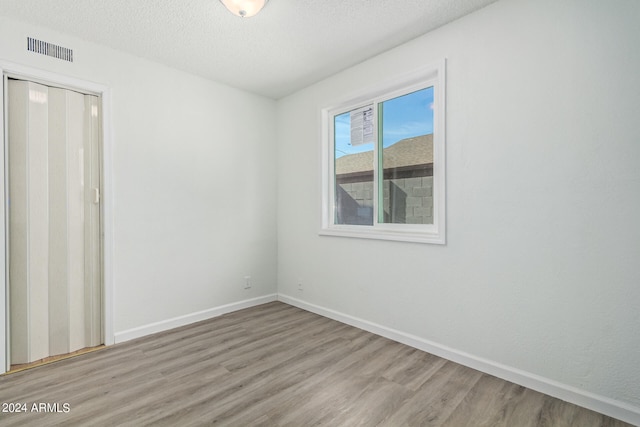 empty room featuring wood-type flooring and a textured ceiling