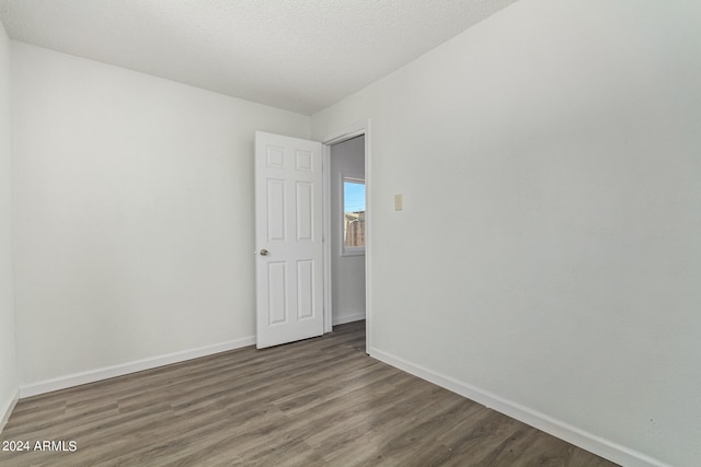 unfurnished room with a textured ceiling and dark wood-type flooring