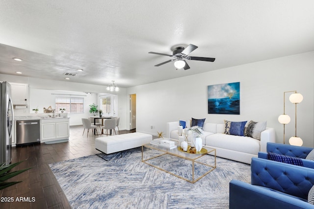 living room featuring sink, ceiling fan with notable chandelier, dark hardwood / wood-style floors, and a textured ceiling