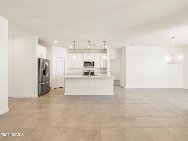 kitchen featuring a kitchen island with sink, white cabinetry, decorative light fixtures, and appliances with stainless steel finishes