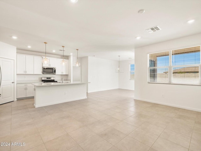 kitchen with a wealth of natural light, pendant lighting, appliances with stainless steel finishes, and white cabinets