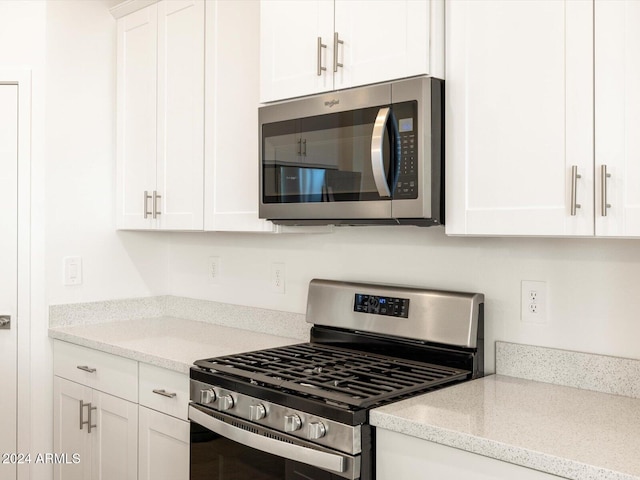 kitchen featuring white cabinetry, stainless steel appliances, and light stone countertops