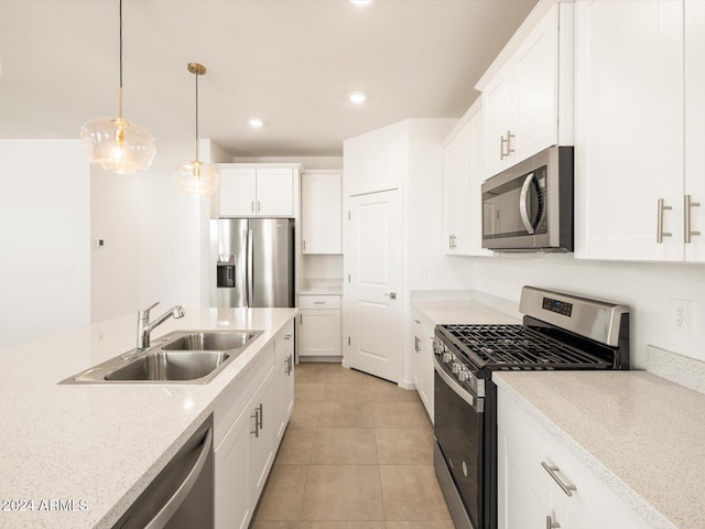 kitchen featuring stainless steel appliances, light stone countertops, hanging light fixtures, sink, and white cabinets