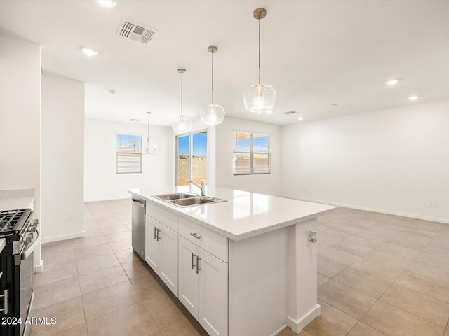 kitchen with sink, an island with sink, pendant lighting, appliances with stainless steel finishes, and white cabinetry