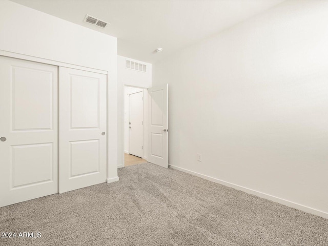 unfurnished bedroom featuring light colored carpet and a closet