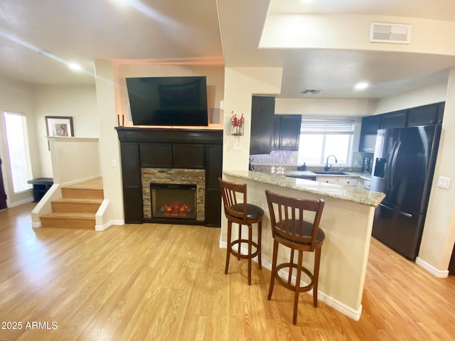 4805 E Kachina Trl Unit 25, Phoenix, AZ 85044 - kitchen featuring refrigerator with ice dispenser, a sink, light wood finished floors, a breakfast bar, and a peninsula