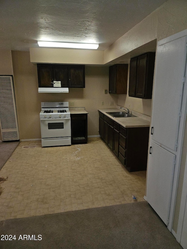 kitchen with dark brown cabinetry, white gas range oven, extractor fan, and sink