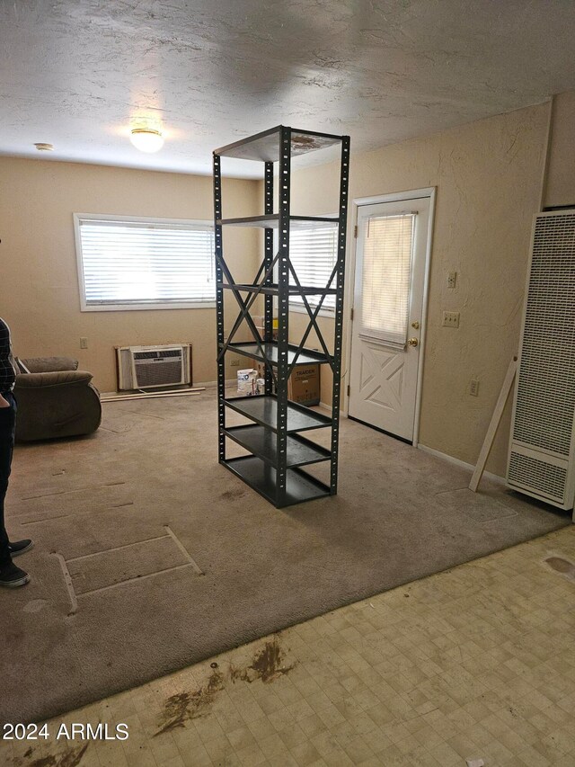 interior space with a wall mounted AC, carpet, and a textured ceiling