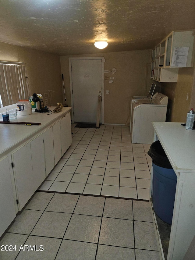 kitchen with white cabinetry, independent washer and dryer, a textured ceiling, and light tile patterned floors