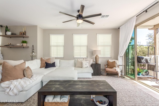 living room with a ceiling fan, visible vents, and wood finished floors