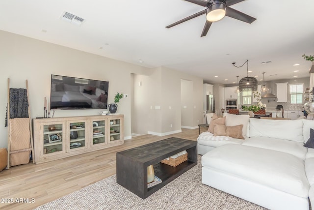 living room with light wood-style flooring, visible vents, baseboards, and recessed lighting