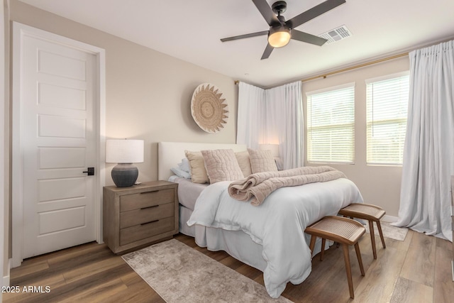 bedroom featuring ceiling fan, visible vents, and wood finished floors