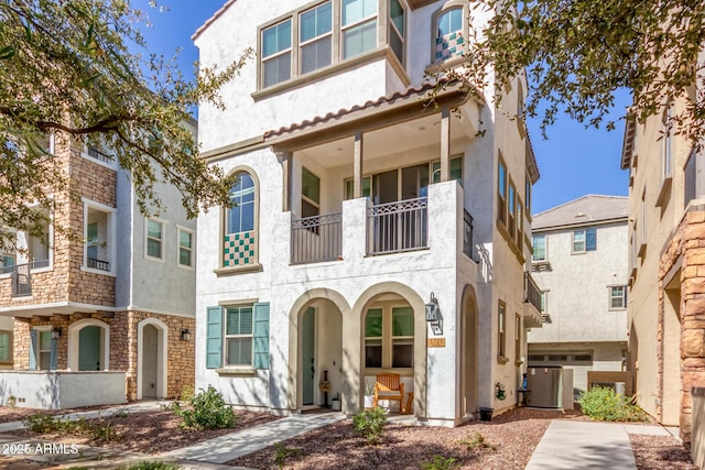 view of front of home with cooling unit, a balcony, and stucco siding