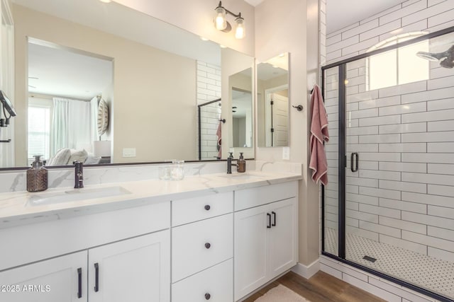 bathroom featuring a stall shower, connected bathroom, and a sink