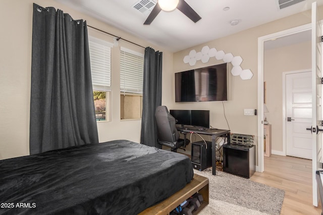 bedroom featuring a ceiling fan, visible vents, baseboards, and wood finished floors